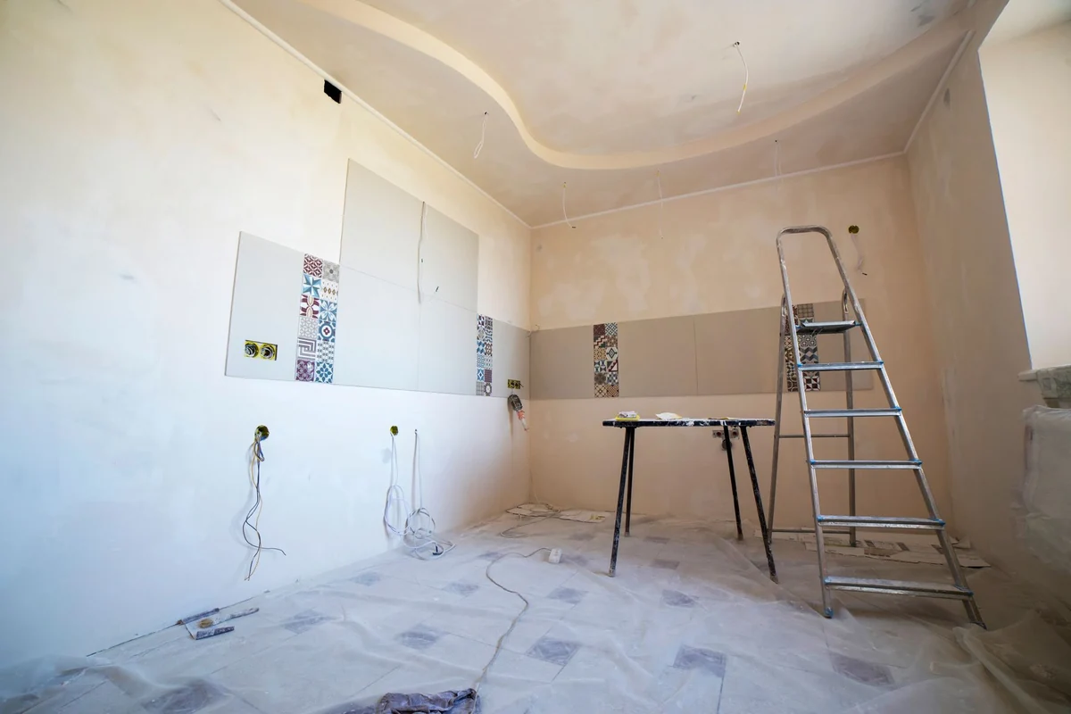 Bathroom under renovation with wall tile samples and a ladder
