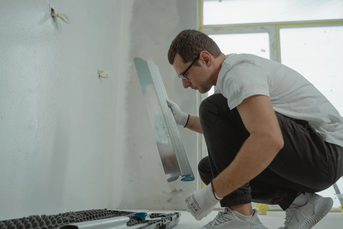Installer smoothing a wall with a large trowel